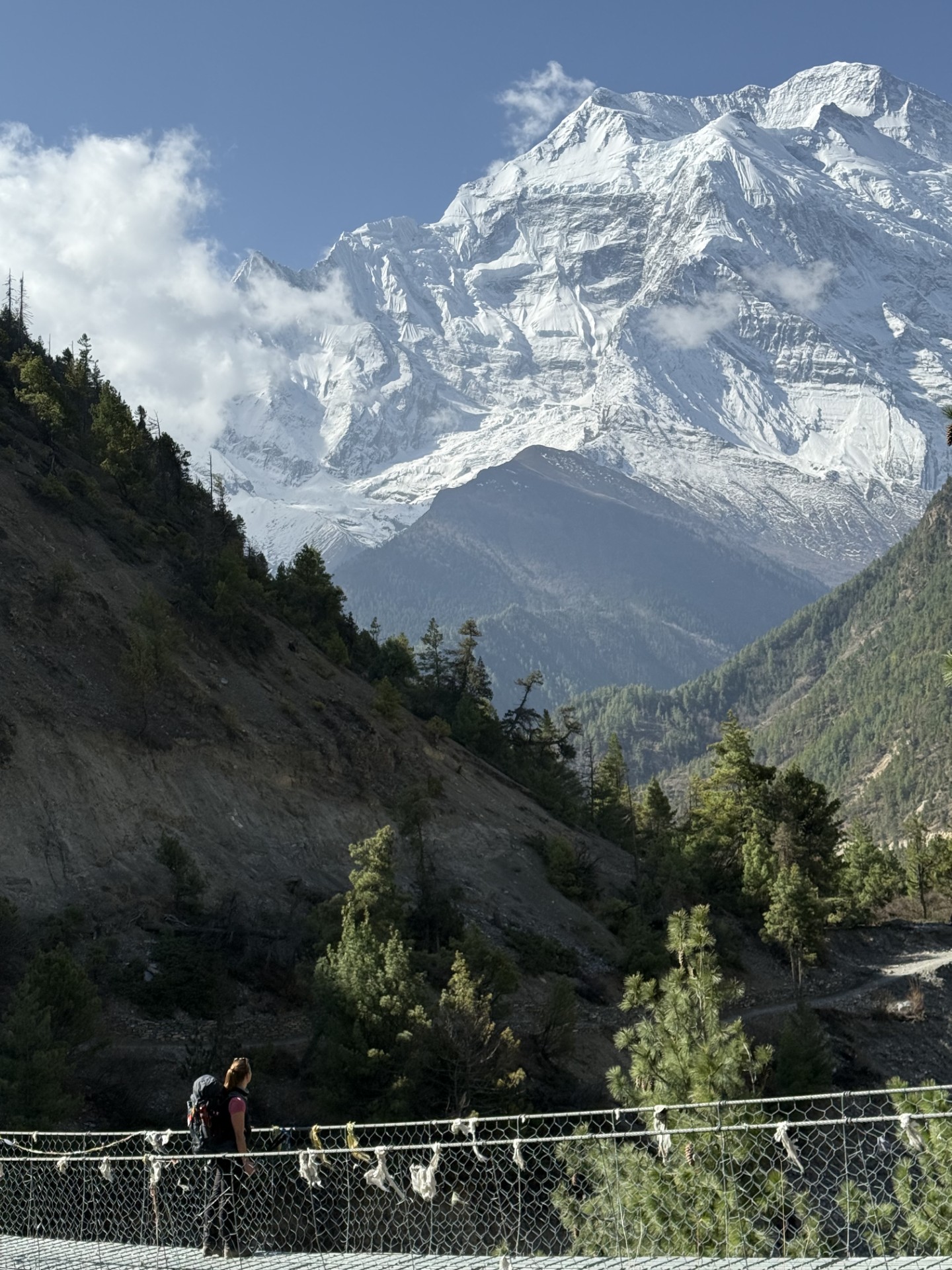 Frau auf einer Hängebrücke vor schneebedeckten Bergen in Nepal, symbolisch für Abenteuer und Selbstvertrauen